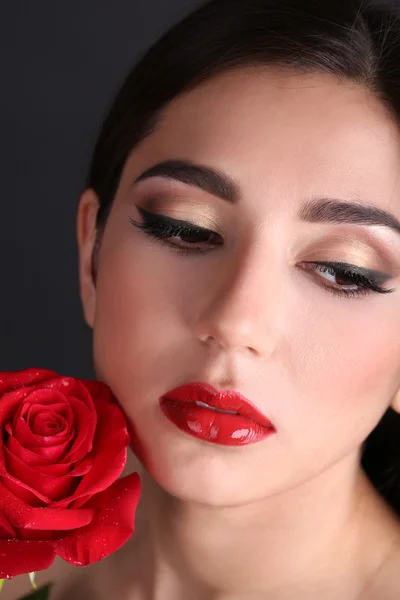 Mädchen mit roten Lippen und Rose auf dunklem Hintergrund — Stockfoto