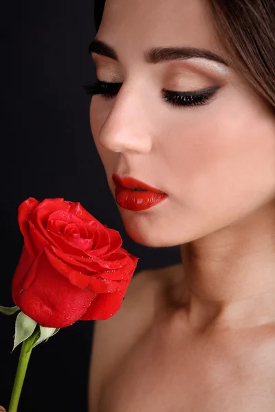 Девушка с красными губами и розой на темном фоне — стоковое фото