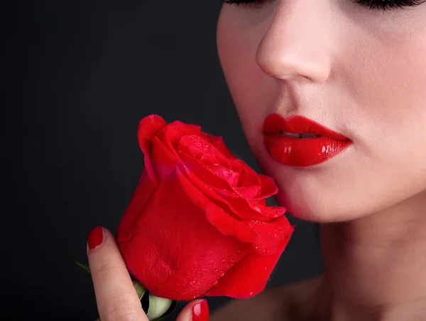 Mädchen mit roten Lippen und Rose auf dunklem Hintergrund — Stockfoto