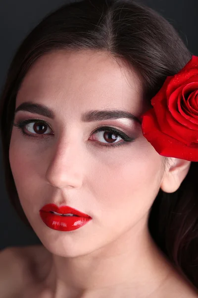Meisje met rode lippen en rose op donkere achtergrond — Stockfoto