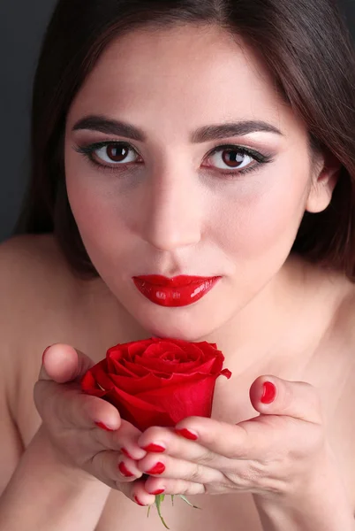 Chica con labios rojos, uñas y rosa sobre fondo oscuro — Foto de Stock