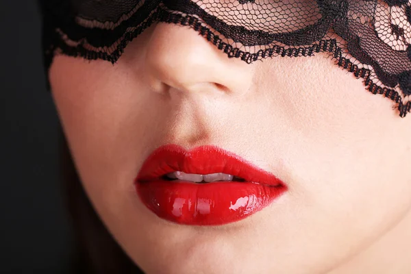 Girl with red lips and openwork black eye shades on dark background — Stock Photo, Image