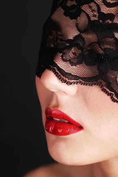 Girl with red lips and openwork black eye shades on dark background — Stock Photo, Image