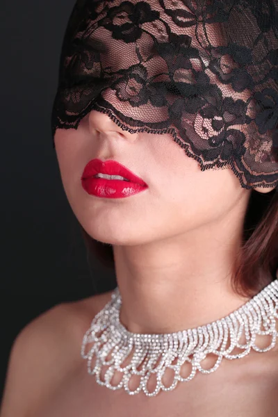 Meisje met rode lippen en opengewerkte zwart oog schaduwen op donkere achtergrond — Stockfoto