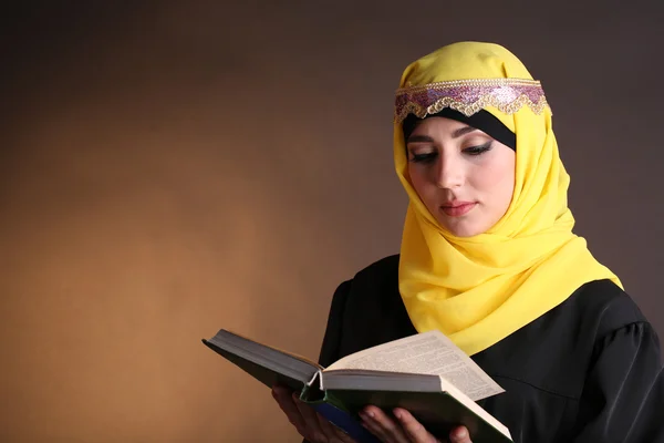 Hermosa mujer árabe musulmana leyendo libro sobre fondo de color oscuro —  Fotos de Stock