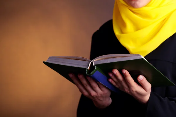 Hermosa mujer árabe musulmana leyendo libro sobre fondo de color oscuro —  Fotos de Stock