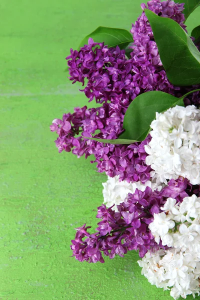 Schöner Strauß fliederfarbener Blumen auf farbigem Holzhintergrund — Stockfoto