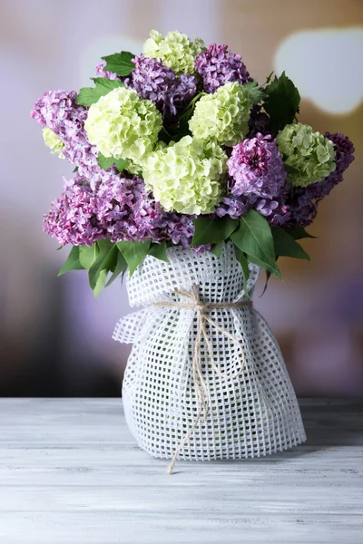 Hermosas flores de primavera en jarrón, sobre mesa de madera, sobre fondo brillante —  Fotos de Stock