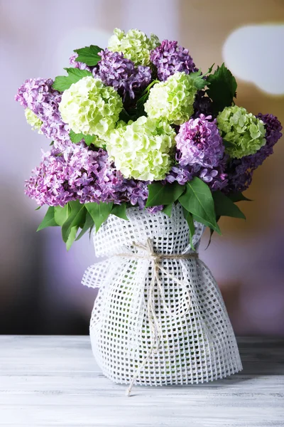 明るい背景上の木製のテーブルの上の花瓶に美しい春の花 — ストック写真
