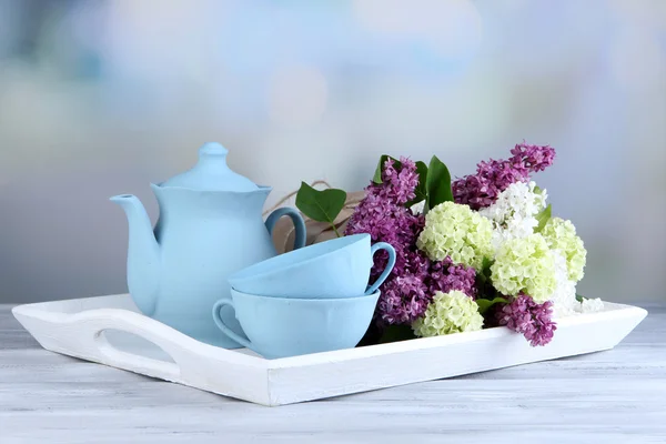 Состав с чайным сервизом и букет красивых весенних цветов на подносе, на деревянном столе, на ярком фоне — стоковое фото