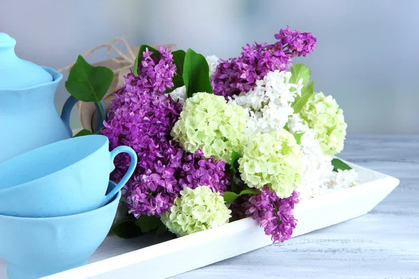 Composición con juego de té y ramo de hermosas flores de primavera en bandeja, sobre mesa de madera, sobre fondo brillante —  Fotos de Stock