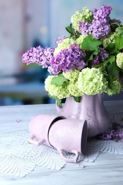 Composizione con tazze da tè e bellissimi fiori primaverili in vaso, su tavolo di legno, su sfondo luminoso — Foto Stock