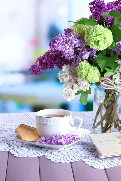 Composizione con tazza di tè, lettere antiche e bellissimi fiori primaverili in vaso, su tavolo di legno, su sfondo luminoso — Foto Stock