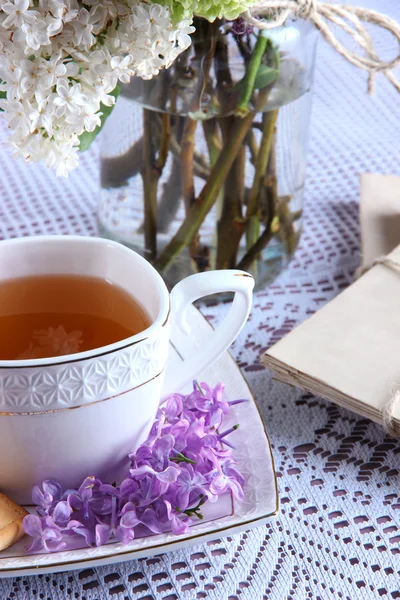 Composição com xícara de chá, cartas antigas e belas flores de primavera em vaso, na mesa de madeira, no fundo brilhante — Fotografia de Stock