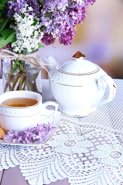 Composición con tetera, taza y hermosas flores de primavera en jarrón, sobre mesa de madera, sobre fondo brillante — Foto de Stock