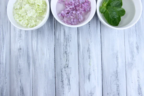Aromatherapie-Behandlungsschalen mit Blumen und parfümiertem Wasser auf Holzgrund — Stockfoto