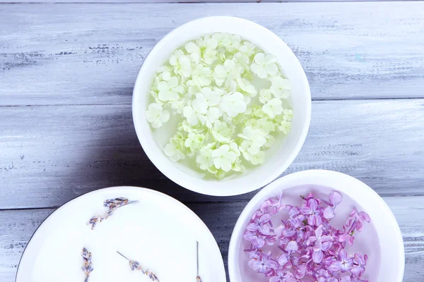 Aromatherapie-Behandlungsschalen mit Blumen und parfümiertem Wasser auf Holzgrund — Stockfoto