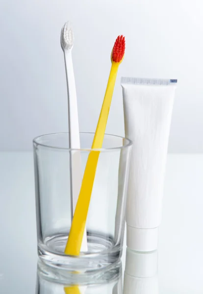 Toothbrushes in glass on light grey background — Stock Photo, Image