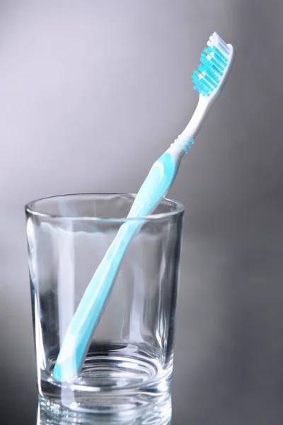 Toothbrush in glass on grey background — Stock Photo, Image