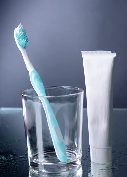 Toothbrush in glass on grey background — Stock Photo, Image