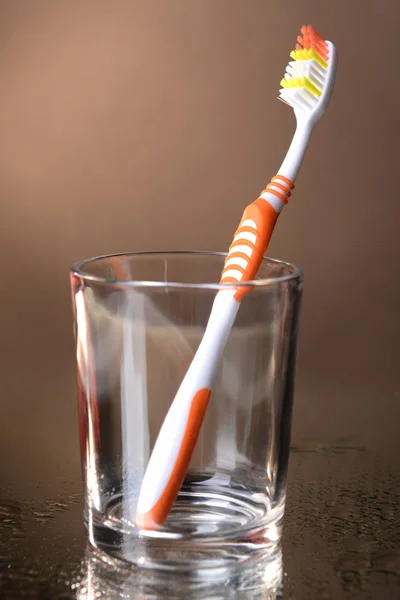 Escova de dentes em vidro sobre fundo marrom — Fotografia de Stock