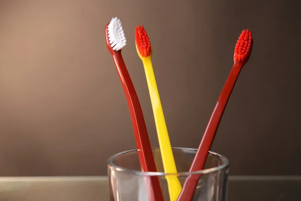 Toothbrushes in glass on brown background — Stock Photo, Image