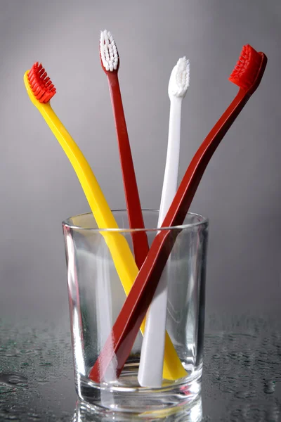 Escovas de dentes em vidro sobre fundo cinza — Fotografia de Stock