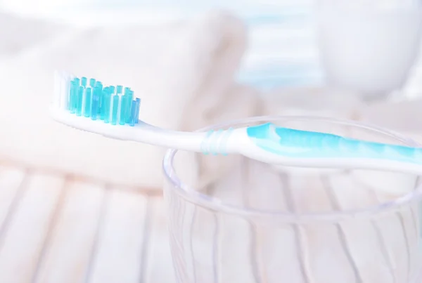 Tandenborstel in glas op tafel op lichte achtergrond — Stockfoto