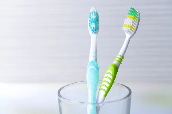 Toothbrushes in glass on table on light background — Stock Photo, Image