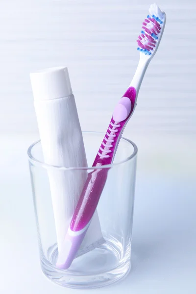 Cepillo de dientes en vidrio sobre mesa sobre fondo claro —  Fotos de Stock