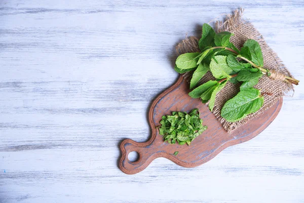Mint on cutting board, on color wooden background — Stock Photo, Image