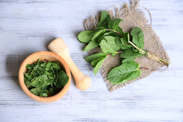 Composition with wooden mortar and mint leaves on  color wooden background — Stock Photo, Image