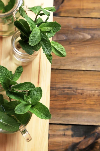 Mint dalam botol kaca pada latar belakang kayu — Stok Foto