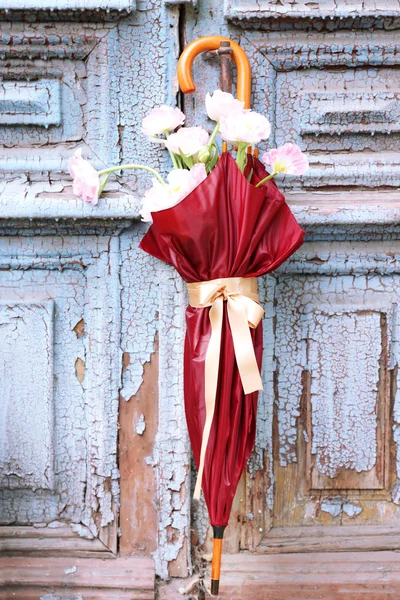 Mooie tulpen in paraplu op oude houten deuren — Stockfoto