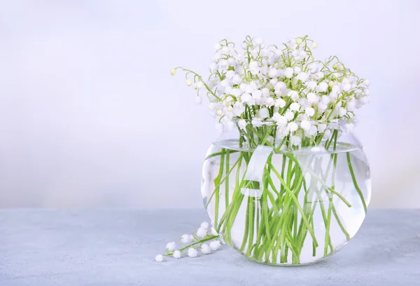 Beautiful lilies of the valley in glass vase on light background — Stock Photo, Image