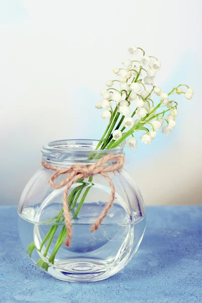 Beautiful lilies of the valley in glass vase on light background — Stock Photo, Image