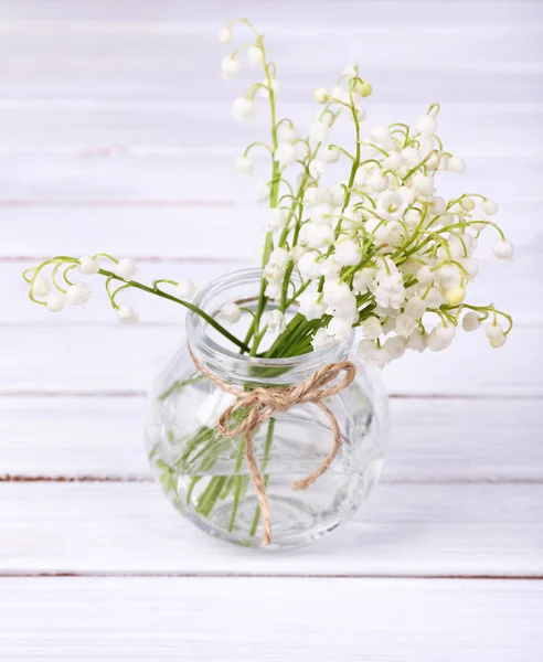 Красивые лилии долины в стеклянной вазе на деревянном столе — стоковое фото