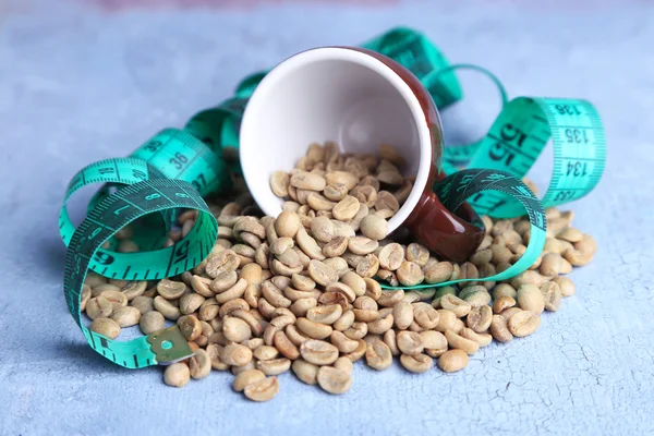 Rohe grüne Kaffeebohnen und Maßband, auf farbigem Holzgrund. Konzept der Gewichtsabnahme — Stockfoto