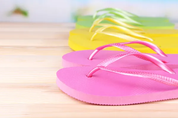 Bright flip-flops on wooden table, on nature background — Stock Photo, Image