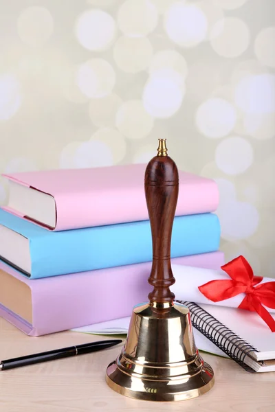 Золотой колокол ретро школы с книгами на столе на ярком фоне — стоковое фото