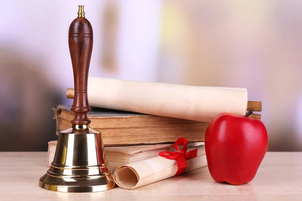 Sino da escola de ouro com material escolar na mesa em fundo brilhante — Fotografia de Stock