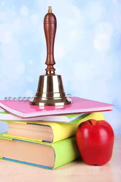 Szkoła złoty dzwon przyborów szkolnych na stole na jasnym tle — Zdjęcie stockowe