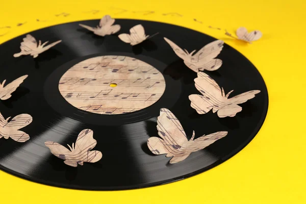 Antiguo disco de vinilo con mariposas de papel, sobre fondo amarillo —  Fotos de Stock