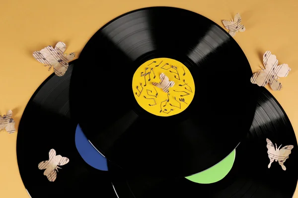 Vieux disques vinyles avec papillons en papier, sur fond brun — Photo