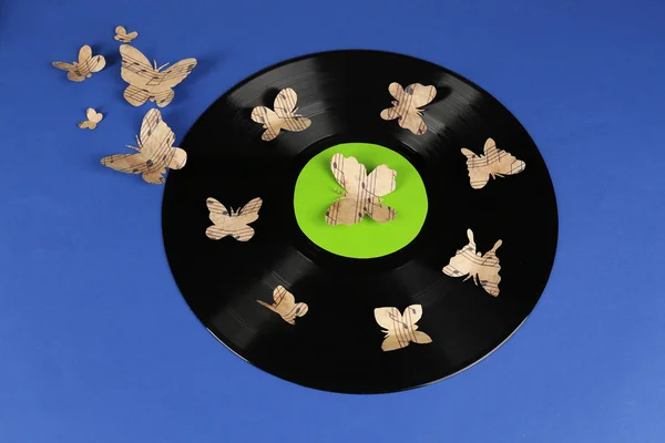 Antiguo disco de vinilo con mariposas de papel, sobre fondo azul — Foto de Stock