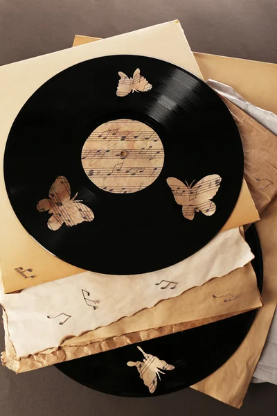 Oude vinylplaten met oud papier en vlinders, op bruine achtergrond — Stockfoto