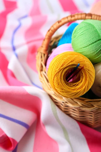 Colorful clews in wicker basket on color napkin background — Stock Photo, Image