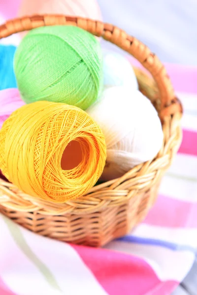 Colorful clews in wicker basket on color napkin background — Stock Photo, Image