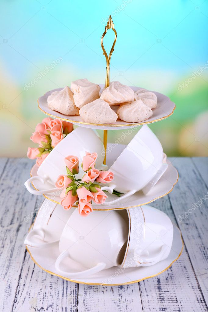 Cups in vase on table on bright background