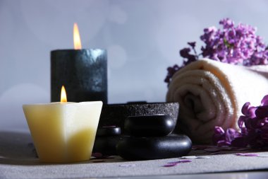 üzerinde açık renkli ahşap masa üzerinde spa tedavisi, havlu ve eflatun çiçekler ile kompozisyon